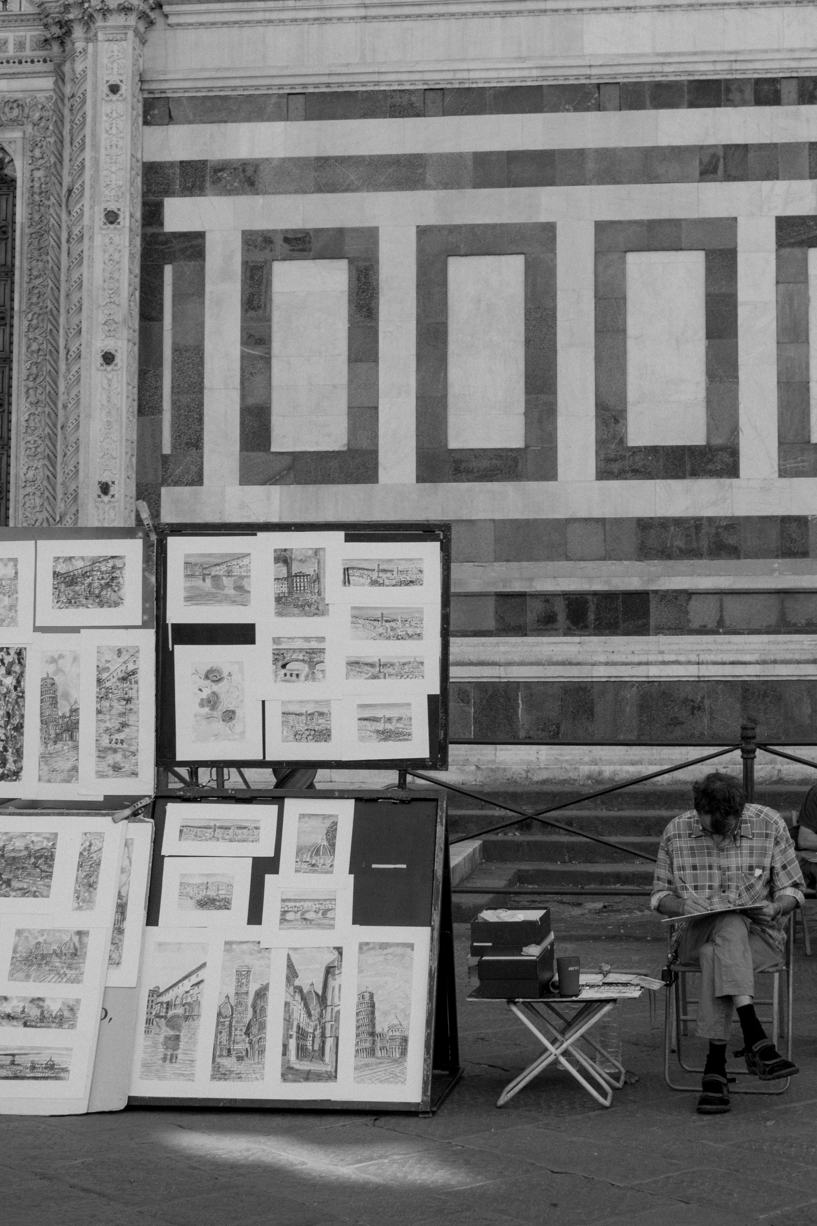black and white image of an artist in Milan, next to his artwork display